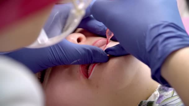 Processo di applicazione del tatuaggio permanente di trucco di rosso sulle labbra donna nel salone di estetista — Video Stock