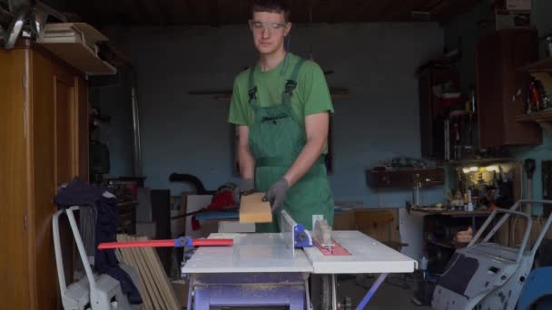 보호용 장갑 과 안경을 쓰고 있는 목수는 자기 집 작업장에 있는 목공 기계 위에 아무것도 없는 나무를 설계한다. 직접 손으로 가구를 만드는 과정. — 비디오