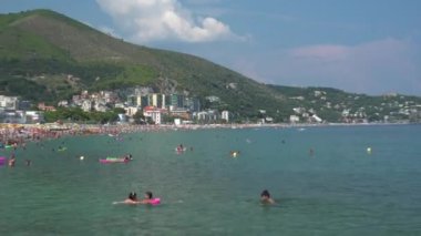 İtalya 'nın Liguria kentindeki yeşil tepelerle çevrili plajdaki insanlar - 4K, Zoom in, El bilgisayarı, Editör