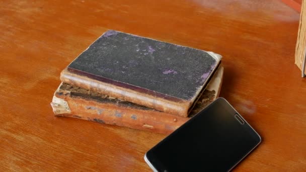Stary smartfon i rzadkie zabytkowe książki na stole w wieku - 4K, Pan — Wideo stockowe