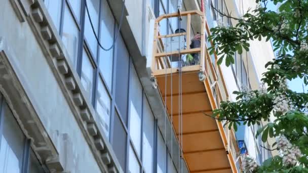 Человек в движущемся строительном лифте и цветущем каштане в Киеве - Редакция, 4К, Tilt — стоковое видео