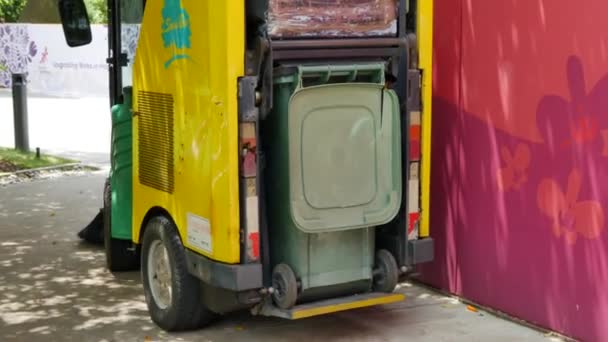 Visão traseira da limpeza do veículo de varredura com lata de lixo na ilha Sentosa em Cingapura - 4K, Áudio, Editorial, Handheld — Vídeo de Stock