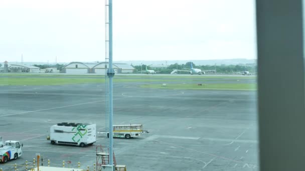Utsikt från fönstren i Denpasar International Airport på flygplan och flygplatsen tjänstebilar - 4K, Redaktionell, Spårning skott — Stockvideo