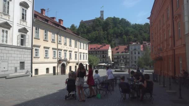 Lidé v venkovní kavárně a pohled na Lublaň Hrad věž s vlajkou, Slovinsko - 4K, Editorial, Audio — Stock video