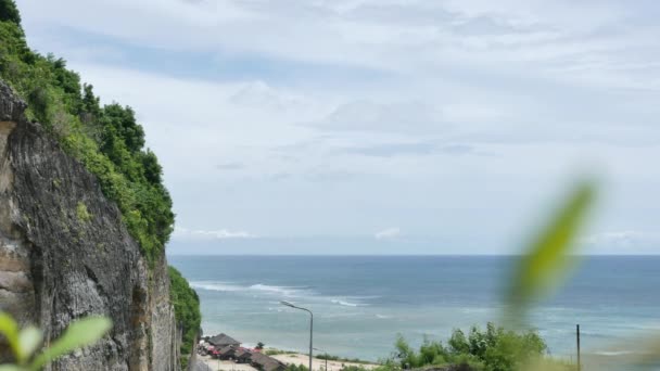 Vista a través de las hojas verdes en la playa de Pandawa, acantilado y el Océano Índico, Bali - 4K, de mano — Vídeo de stock