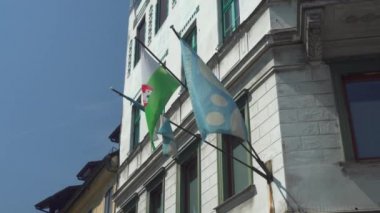 Ljubljana, Slovenya 'da güneşli bir yaz gününde binada bayraklar - 4K, Editör, El bilgisayarı