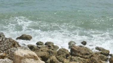 Ön planda Rocky sahili ve Pandawa Sahili yakınlarında manzaralı Hint Okyanusu dalgaları - 4K, El bilgisayarı