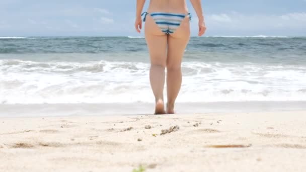 Perempuan memasuki bingkai dan kemudian pergi ke arah gelombang Samudera Hindia di Pantai Pandawa, Bali - 4K — Stok Video