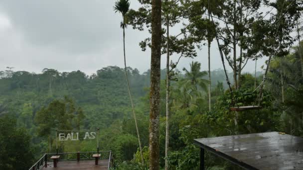 Wet empty tourist terrace, swing and magnificent view on jungles in the rain in Bali - 4K — Video