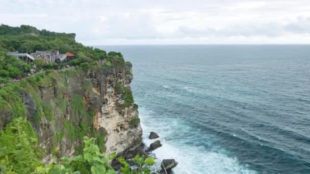 ウルワツ寺院の崖、前景のインド洋と緑の植物の美しい波、バリ- 4K 、ワイドショット — ストック動画