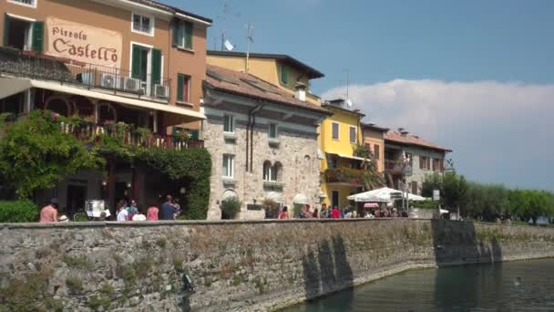 Οι τουρίστες περπατούν στο δρόμο η τάφρος στο Sirmione το καλοκαίρι στην Ιταλία - 4K, Editorial, Ευρεία βολή, Handheld — Αρχείο Βίντεο