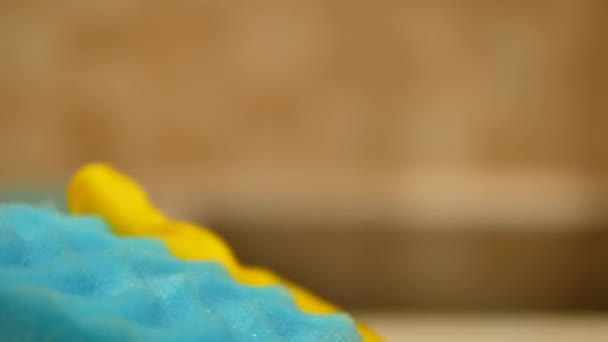 Ruční v žluté čisticí rukavici drží modrou čisticí houbu - 4K, zblízka