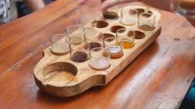 Turistler, Kopi Luwak Çiftliği, Bali 'de çeşitli egzotik içecekler içerken ellerini kullanıyor. 4K, el bilgisayarı, yakın çekim.