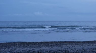 Deniz dalgaları ve volkanik çakıl taşlı plaj güneş doğmadan bir saat önce Amed, Bali 'de - 4K