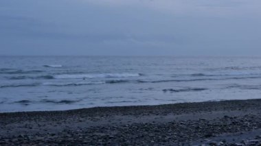 Siyah volkanik çakıl taşlı plaj ve deniz dalgaları Amed, Bali 'de güneş doğmadan bir saat önce - 4K