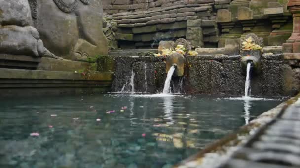 Czyste strumienie świętej wody źródlanej i dekoracje kamienne w świątyni Pura Tirta Empul - 4K, Niski kąt — Wideo stockowe