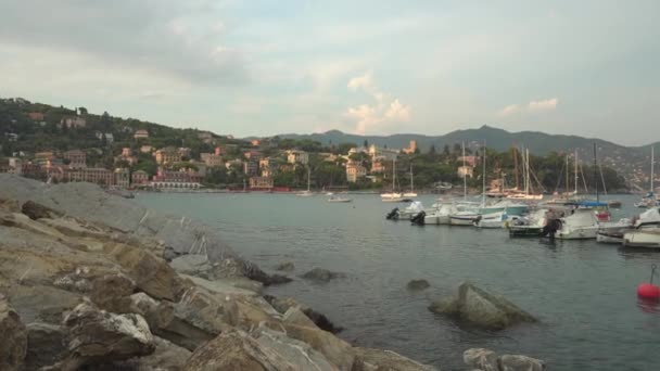 Barcos cerca de la costa rocosa en Rapallo a la hora dorada, Italia - 2K, Amplio tiro, Pan, Portátil — Vídeos de Stock