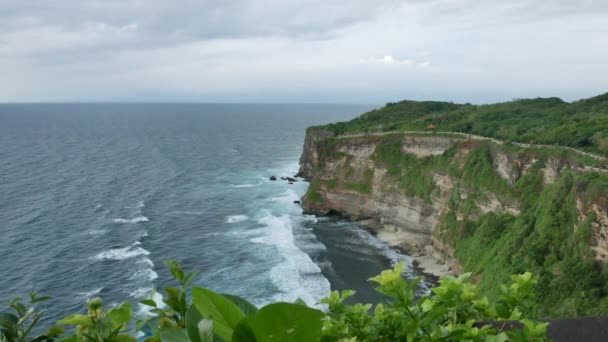 Gyönyörű zöld szikla az Uluwatu templomnál és türkiz hullámok az Indiai-óceánnál, Bali - 4K, széles lövés, kézi — Stock videók