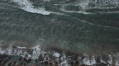 Akşamları Uluwatu Tapınağı yakınlarında volkanik kayalık bir sahilin ve Hint Okyanusu 'nun destansı dalgalarının en üst görüntüsü - 4K, El bilgisayarı