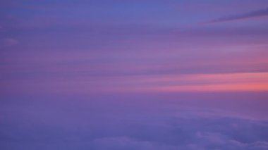 Bulutların üstündeki uçaktan gün batımında pembe ve eflatun rengi gökyüzüne bak. 4K, El bilgisayarı