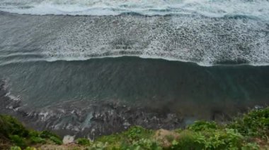 Bali, INDONEZYA - 22 Ocak 2018: güzel Hint Okyanusu dalgaları, yeşil uçurum ve Bali 'deki Uluwatu tapınağı yakınlarındaki volkanik kıyı. 4K, Geniş açı, El bilgisayarı, Üst Görünüm