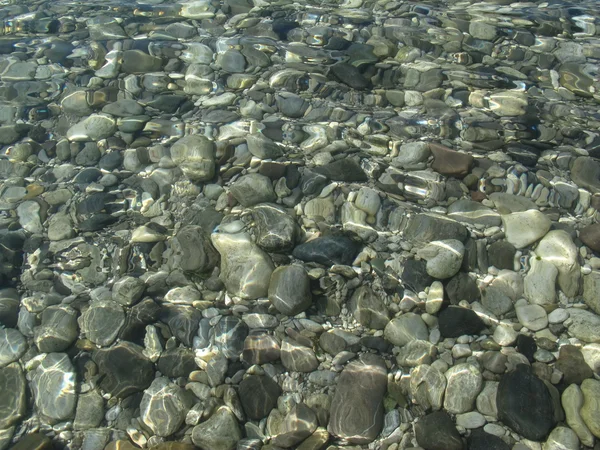 Schöne bunte Kieselsteine, klares Wasser. — Stockfoto