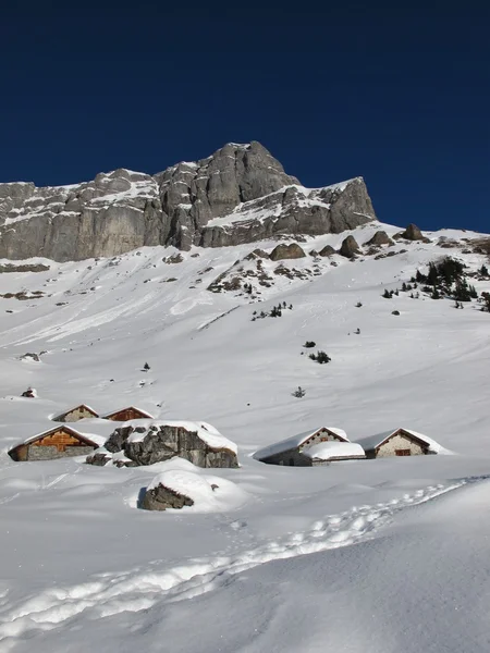 Hóval borított kunyhók és a hegyek közelében Braunwald — Stock Fotó