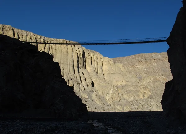 Silhouettes of a suspension bridge and limestone cliffs, Nepal — Stock Photo, Image
