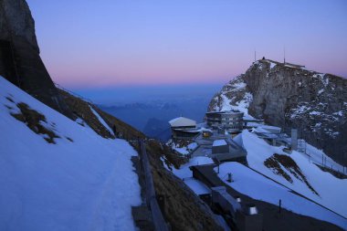 Gün batımında pembe gökyüzü. Pilatus Dağı 'nın zirve istasyonu ve otelleri.