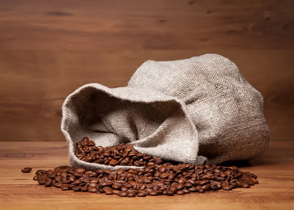 Canvas bag with coffee beans on rustic table with wooden texture — Stock Photo, Image