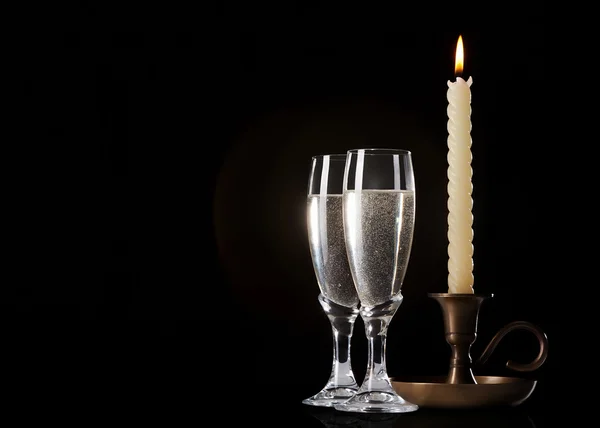 Due bicchieri di champagne e candela su sfondo nero — Foto Stock