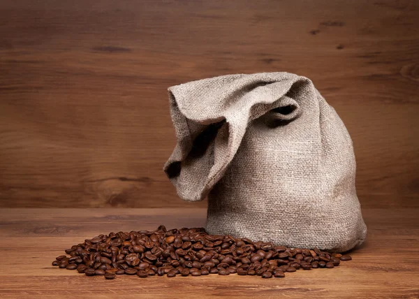 Canvas bag with coffee beans on rustic table with wooden texture — Stock Photo, Image