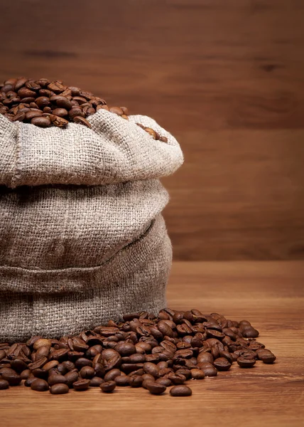 Canvas bag with coffee beens on rustic table with wooden texture — Stock Photo, Image