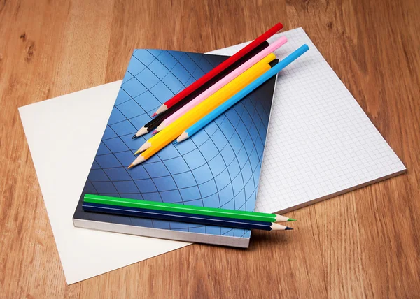 Pencils and notebook on wooden table — Stock Photo, Image