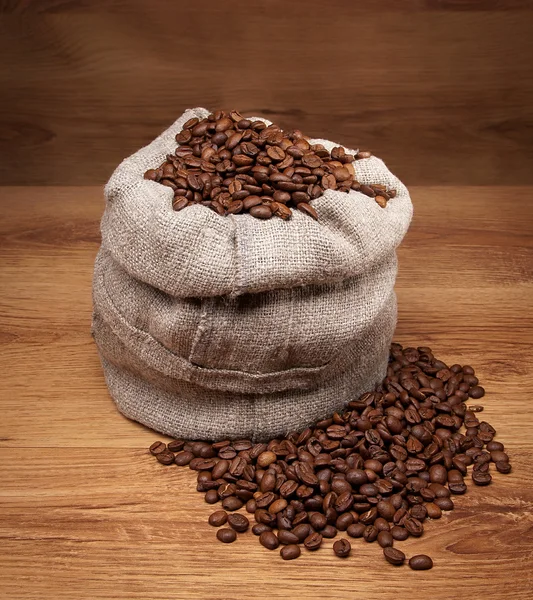 Canvas bag with coffee beens on rustic table with wooden texture — Stock Photo, Image