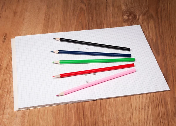 Crayons et cahier sur table en bois — Photo