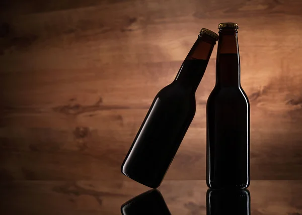 木製テクスチャ上の 2 つのビール瓶のクローズ アップ — ストック写真