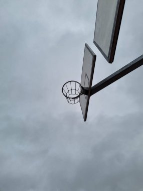Farklı seviyelerde zincir ağları olan açık hava basketbol halkaları. Aşağıdan manzaralı sokak basketbolu potası. Hava bulutluyken sokak sporu.