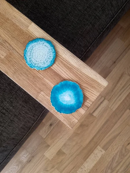 Narrow wooden table with two glass coasters. Epoxy resin coasters laying at the laptop table. Living room interior details.