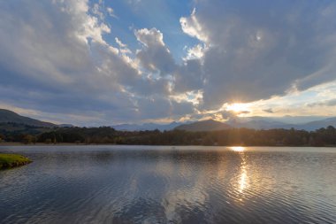 Güneş, gün batımında su üzerinde bulutların arasından yıldız patlaması yaptı.