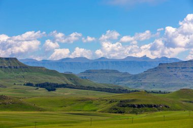Mavi dağların ve yeşil vadinin üzerinde beyaz bulutlar