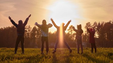 Çocukların silueti neşeyle zıplıyor, Güneşin güzel, parlak günbatımında mutlu bir çocukluk zamanı