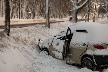 During the accident, the car drove off a slippery winter road. A broken car after an accident in a snowdrift. The driver lost control of the car on a slippery road in icy conditions