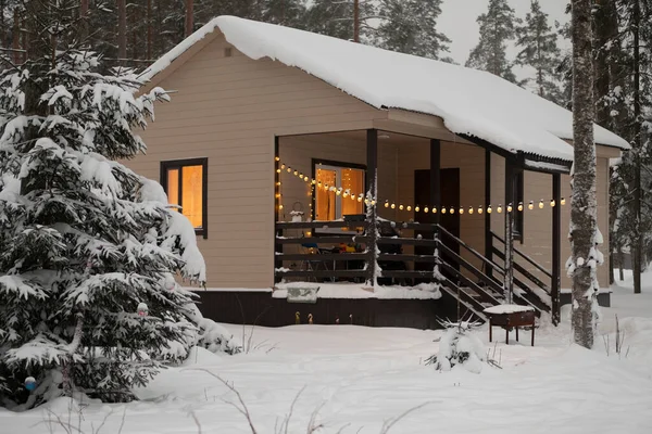 雪の中の灰色の空に屋根の上に雪のある木造の家 建物の建築 森の中に建設中の家の高品質の写真 ロイヤリティフリーのストック画像