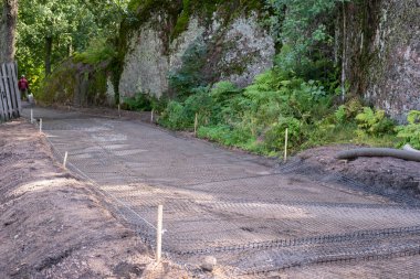 Ormanda kayaların arasında bir yol inşaatı, yolun çamur akıntılarıyla aşınmasını önlemek için bir şebeke kurulumu.