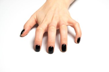 Yapışır, gerilir, tutunur, gerilir ya da çizilir. Siyah ojeli kadın eli, beyaz bir arka planda el kol hareketi yapıyor.