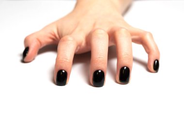 Yapışır, gerilir, tutunur, gerilir ya da çizilir. Siyah ojeli kadın eli, beyaz bir arka planda el kol hareketi yapıyor.