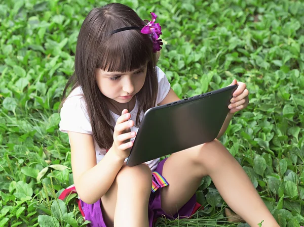 Fille avec tablette pc dans la prairie — Photo