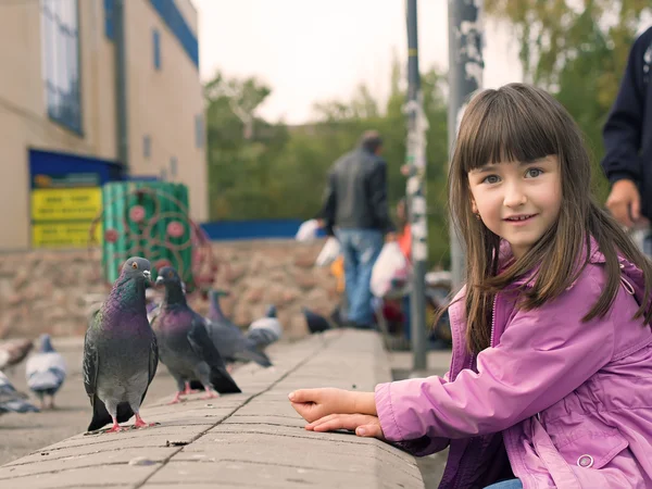Small caucasian girl feeding pigeons — Stock Photo, Image