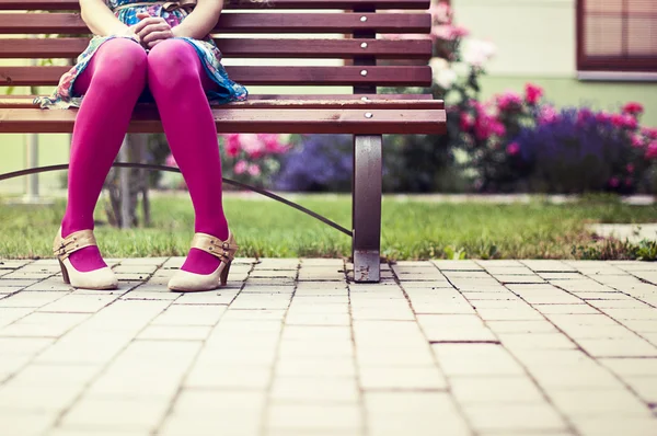Mulher com meias rosa sentado no banco Imagens Royalty-Free